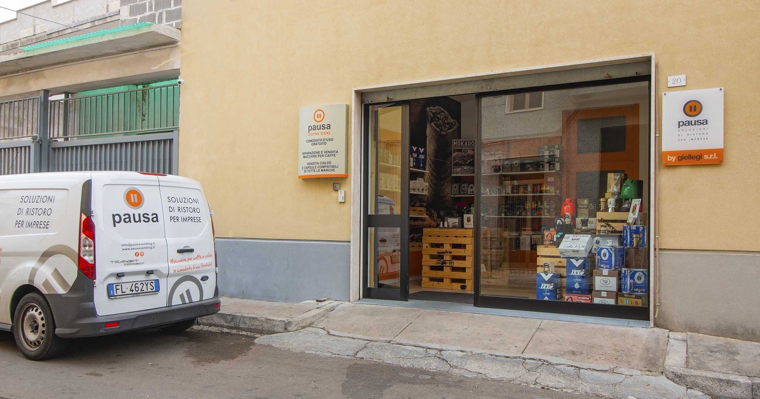 Furgone bianco Pausa davanti al coffee store con vetrina di confezioni di caffè su pallet di legno e insegna arancione